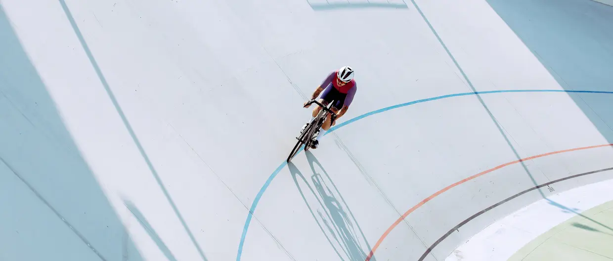 A cyclist on a bicycle track riding along curves (cropped).