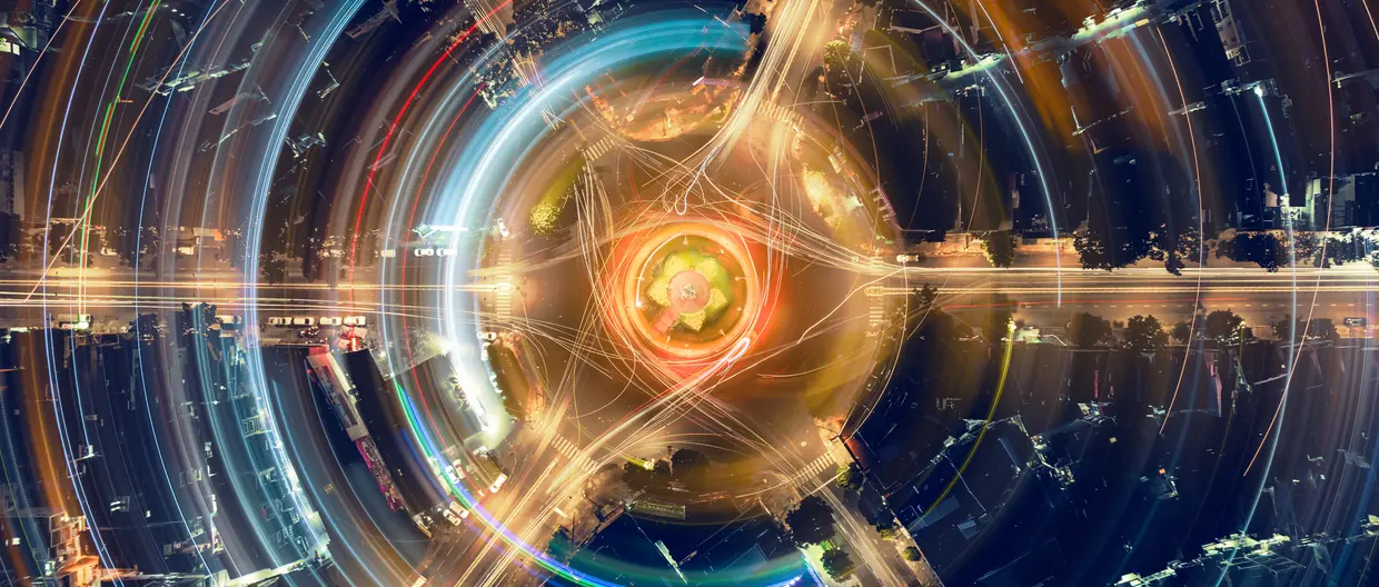 An artistic, abstract depiction of light trails, using long-exposure photography of a city roundabout
