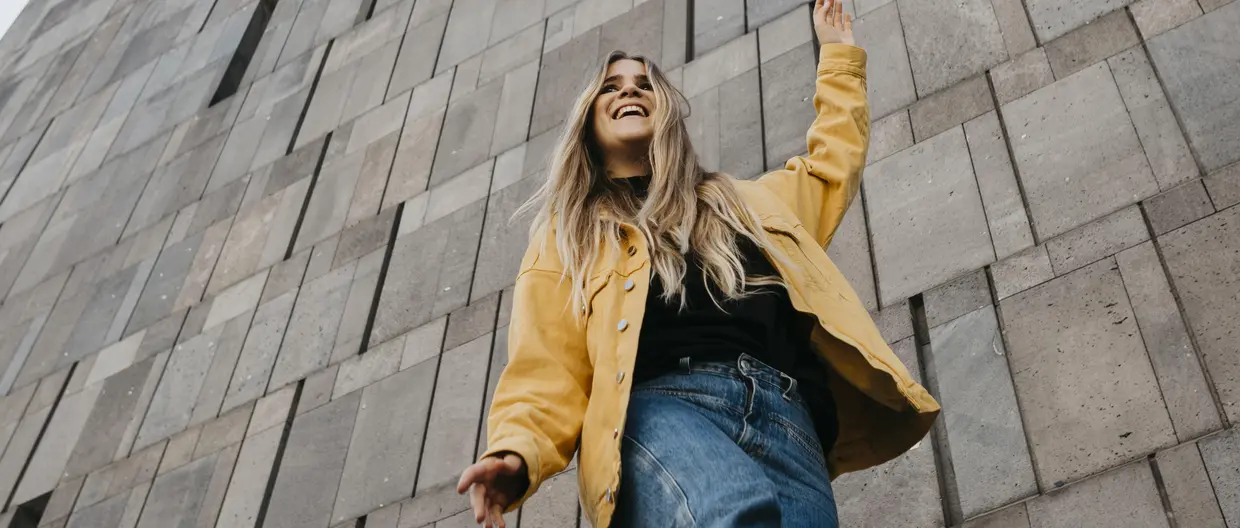 Woman in yellow jacket in front of wall