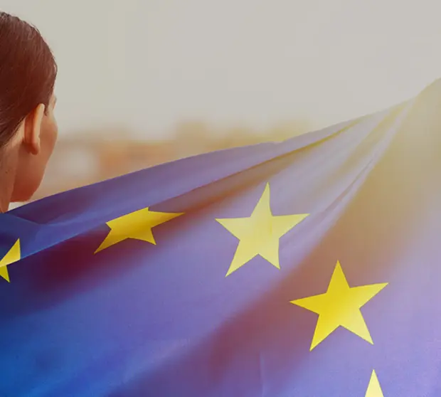 A woman wrapped in the European Union flag and looking towards the sunset