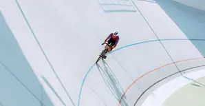 A cyclist on a bicycle track riding along curves (cropped).