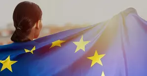 A woman wrapped in the European Union flag and looking towards the sunset