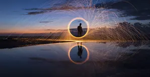A long-exposure photograph capturing light trails from burning steel wool being spun
