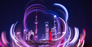 A dynamic, long-exposure photograph of the Shanghai skyline, featuring the Oriental Pearl Tower and other skyscrapers, taken using a camera rotation technique.