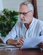 A senior man studying in front of his laptop