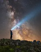 Man looking up a starry sky with a torchlight