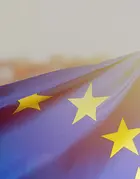 A woman wrapped in the European Union flag and looking towards the sunset