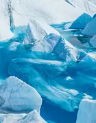 A woman watching a pool of water in a huge glacier