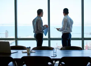 2 coworkers talking in a office with a ocean view