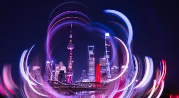 A dynamic, long-exposure photograph of the Shanghai skyline, featuring the Oriental Pearl Tower and other skyscrapers, taken using a camera rotation technique.