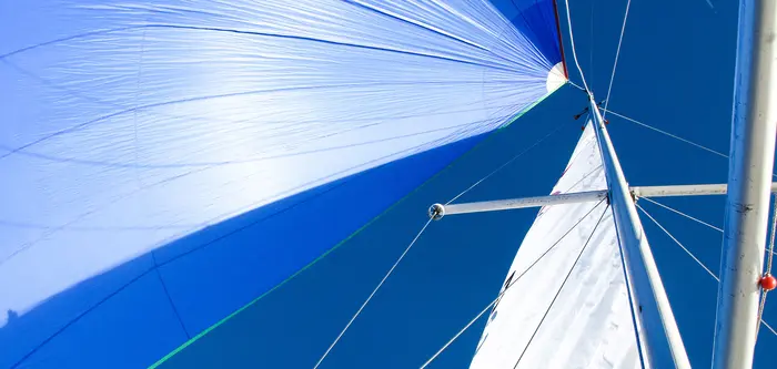The sails and the mast of a sailboat viewed from below.