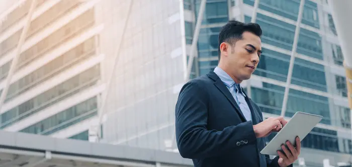 businessman looking a his tablet in the street