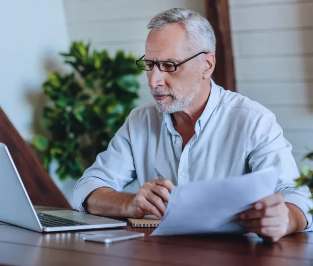 A senior man studying in front of his laptop