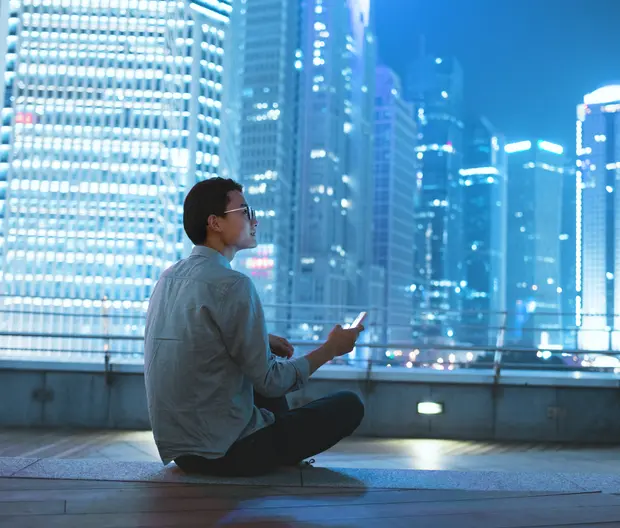 Mann mit Telefon im Aparatment mit Aussicht auf Skyline