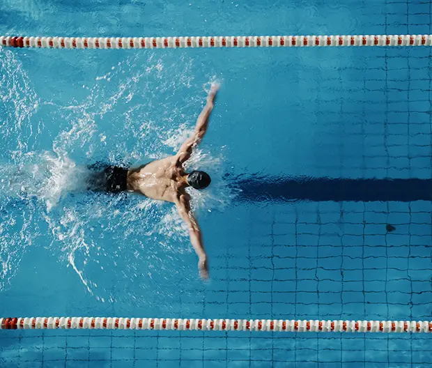 A male swimmer in a swimming pool corridor