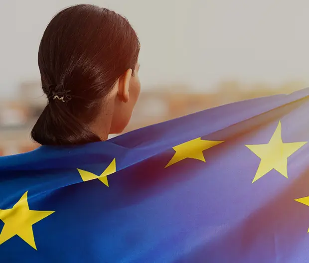 A woman wrapped in the EU flag watching the sunset.