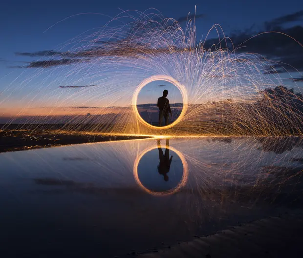 A long-exposure photograph capturing light trails from burning steel wool being spun