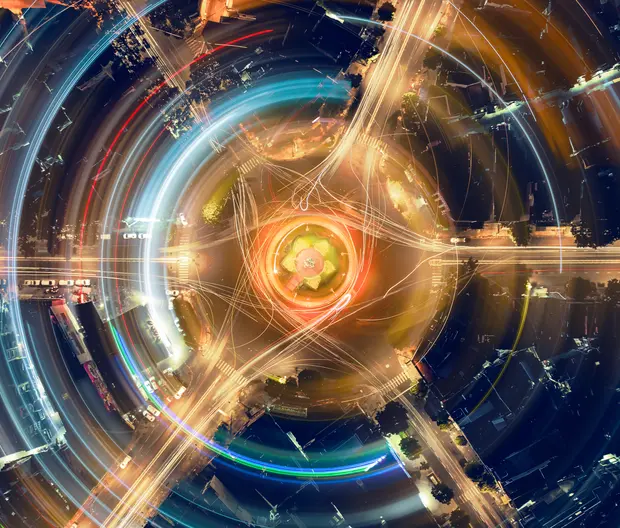 An artistic, abstract depiction of light trails, using long-exposure photography of a city roundabout