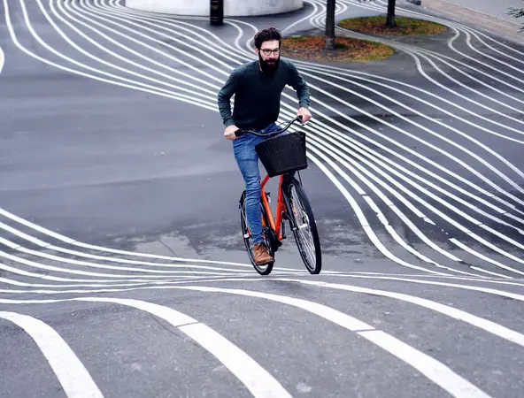 Man on bicycle riding up lined hill