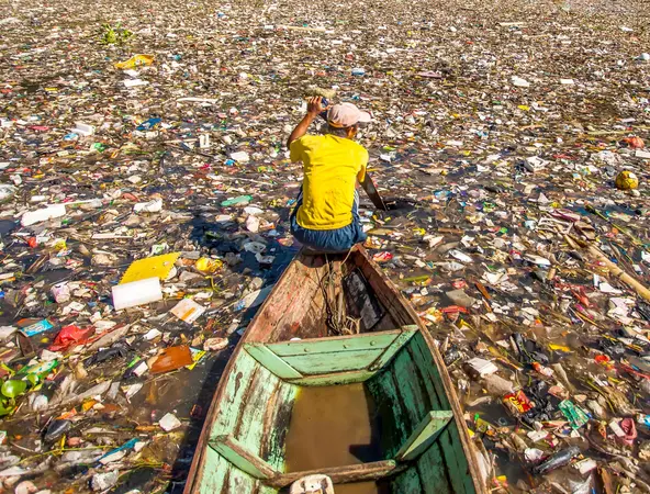 A man in boat in a river of garbage