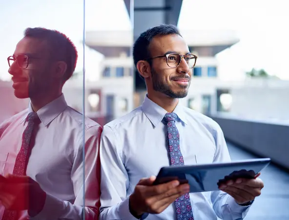 A smiling young businessman next to a window