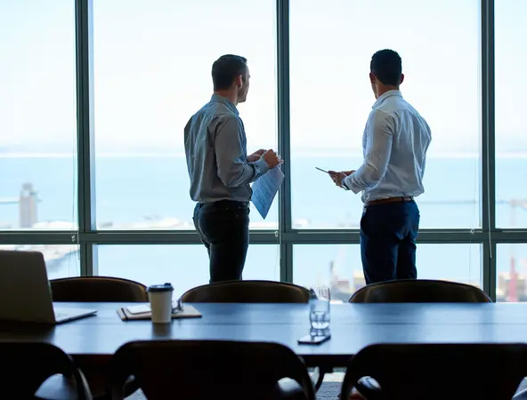 2 coworkers talking in a office with a ocean view