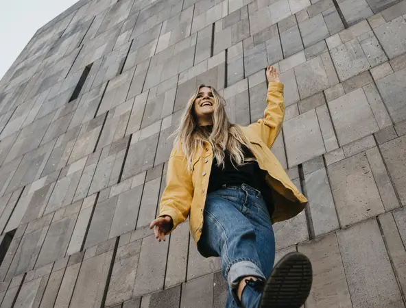 Woman in yellow jacket in front of wall