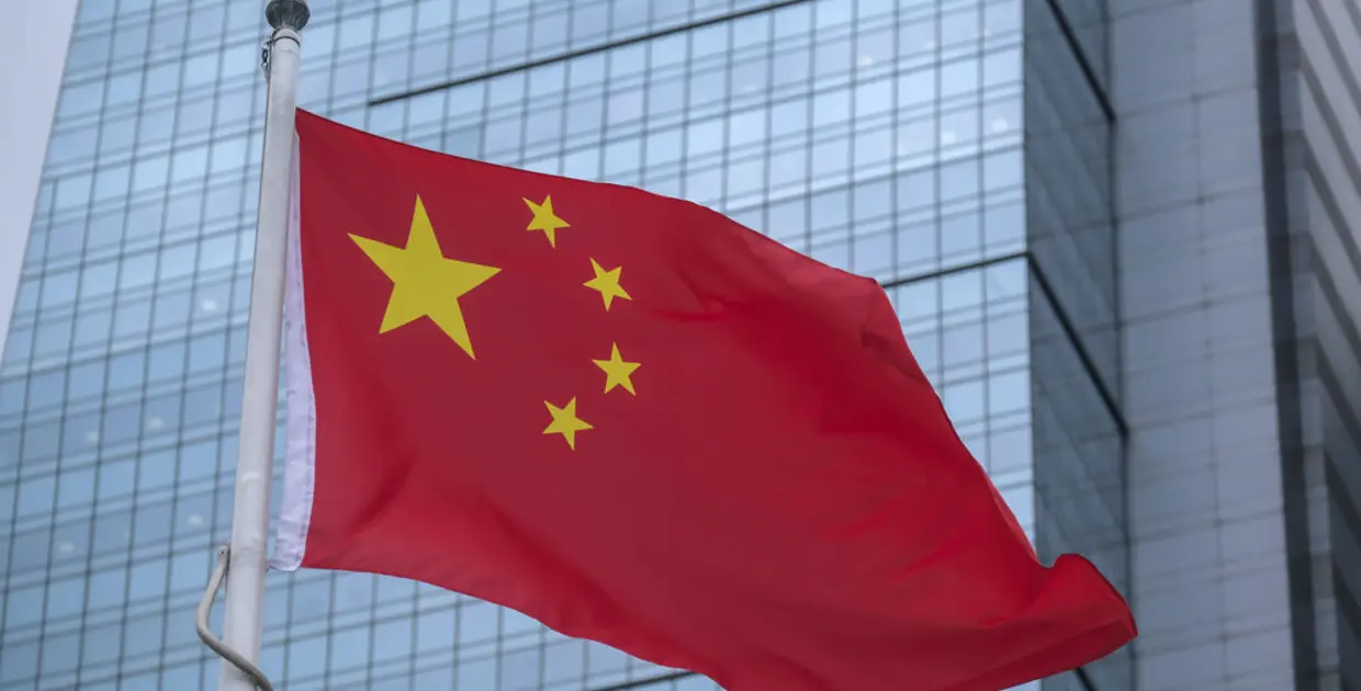 Drapeau chinois devant un bâtiment moderne, symbolisant les affaires et la finance.