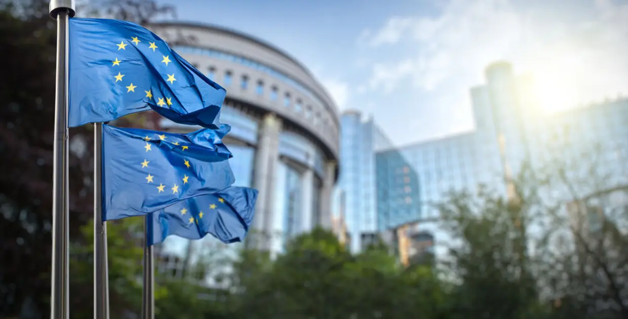 Bannière de l'Union européenne devant un bâtiment moderne, contexte de gestion financière.