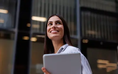 Salariée d'une entreprise qui regarde vers le ciel avec une tablette dans les mains.