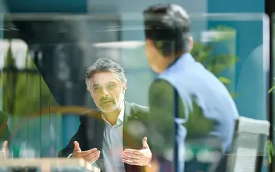 Deux experts financiers discutent dans les bureaux d'Amundi, entourés de verdure.
