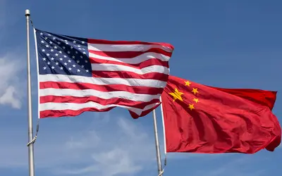 Drapeaux chinois et américain flottant côte à côte, symbolisant le commerce international.