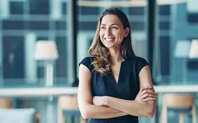 Femme avec les bras croisés, dans les bureaux d'Amundi, symbole de l'expertise en gestion d'actifs.