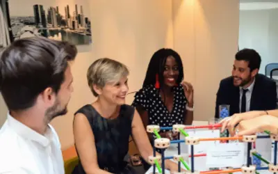 Quatre professionnels en épargne salariale collaborent autour d'une maquette dans les bureaux d'Amundi.