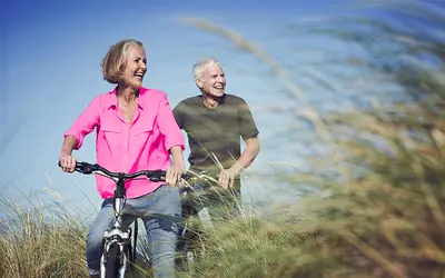 Couple senior heureux se promenant à vélo, arrière-plan de nature et ciel bleu.