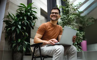 Un gestionnaire d'actifs souriant travaille sur un ordinateur portable dans les bureaux d'Amundi.