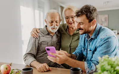 Un gestionnaire d'actifs montre des informations financières sur son téléphone à deux personnes âgées.