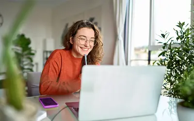 Une experte en gestion d'actifs souriante travaille sur son ordinateur dans les bureaux d'Amundi.