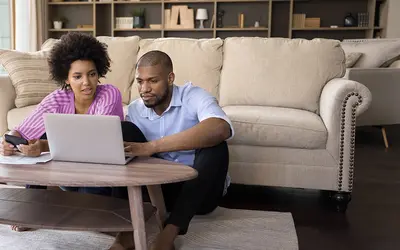 Un couple examine des investissements sur un ordinateur portable dans un cadre confortable.