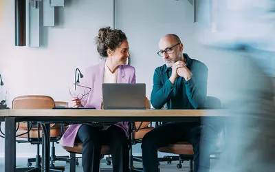 Deux experts financiers discutent devant un ordinateur dans les bureaux d'Amundi.