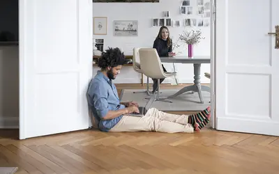 Un expert financier assis sur le sol, travaillant avec une tablette, dans les bureaux d'Amundi.