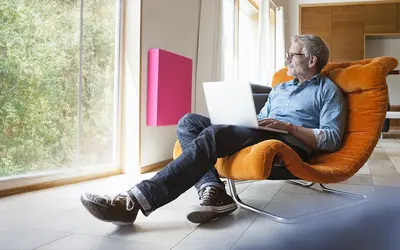 Expert en gestion d'actifs dans un fauteuil, travaillant sur un ordinateur dans un bureau lumineux.