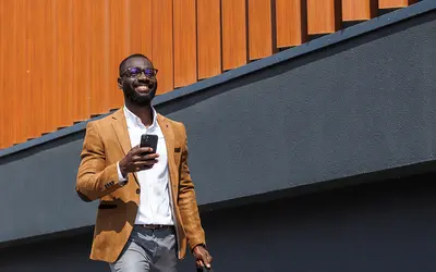 Un gestionnaire d'actifs souriant marchant dans un milieu urbain moderne.