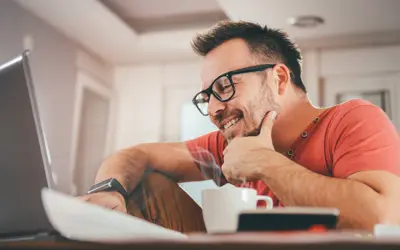 Un gestionnaire d'actifs souriant travaillant sur un ordinateur dans un bureau moderne.