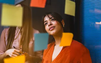 Femme qui regarde un mur de post-its colorés.