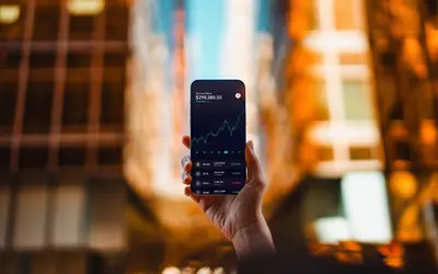 Un expert en finance tient un smartphone affichant une courbe de croissance financière.