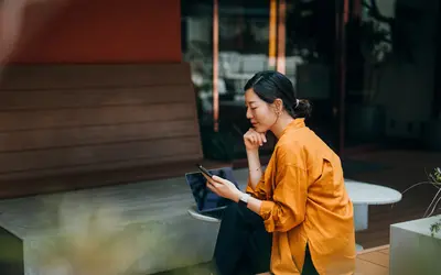 Femme asiatique qui consulte l'actualité sur son téléphone.