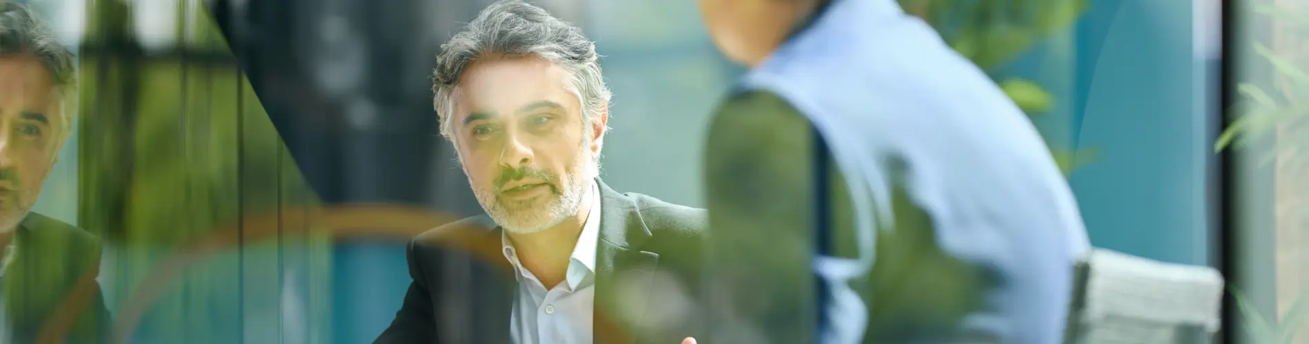 Deux experts financiers discutent dans les bureaux d'Amundi, entourés de verdure.