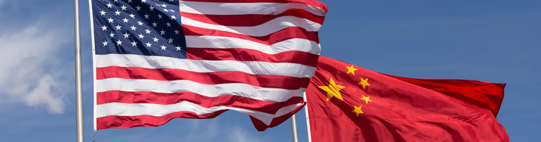 Drapeaux américain et chinois flottant sous un ciel dégagé, symbolisant les relations économiques.