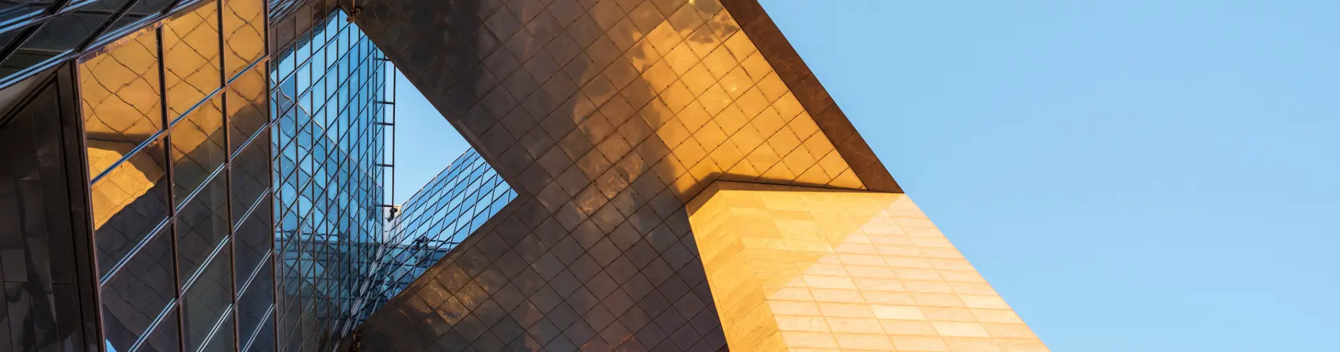 Architecture moderne à l'extérieur des bureaux d'Amundi, reflet doré sous le ciel bleu.